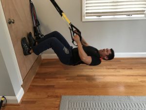 A man is hanging on the wall with a trx.