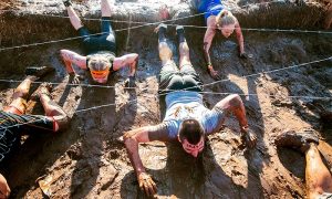 A group of people are crawling through mud.