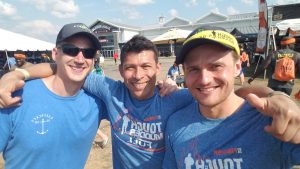 Three men in blue shirts and hats posing for a picture.